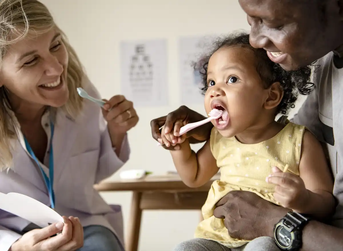 Parent brushing a baby's teeth with a soft brush
